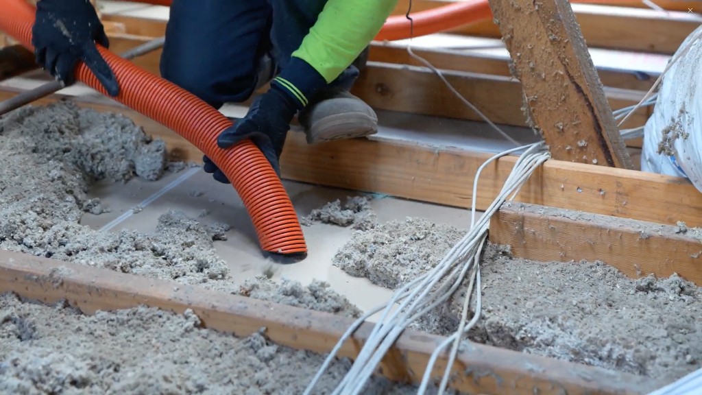Installer extracting old insulation from a ceiling with an industrial vacuum hose